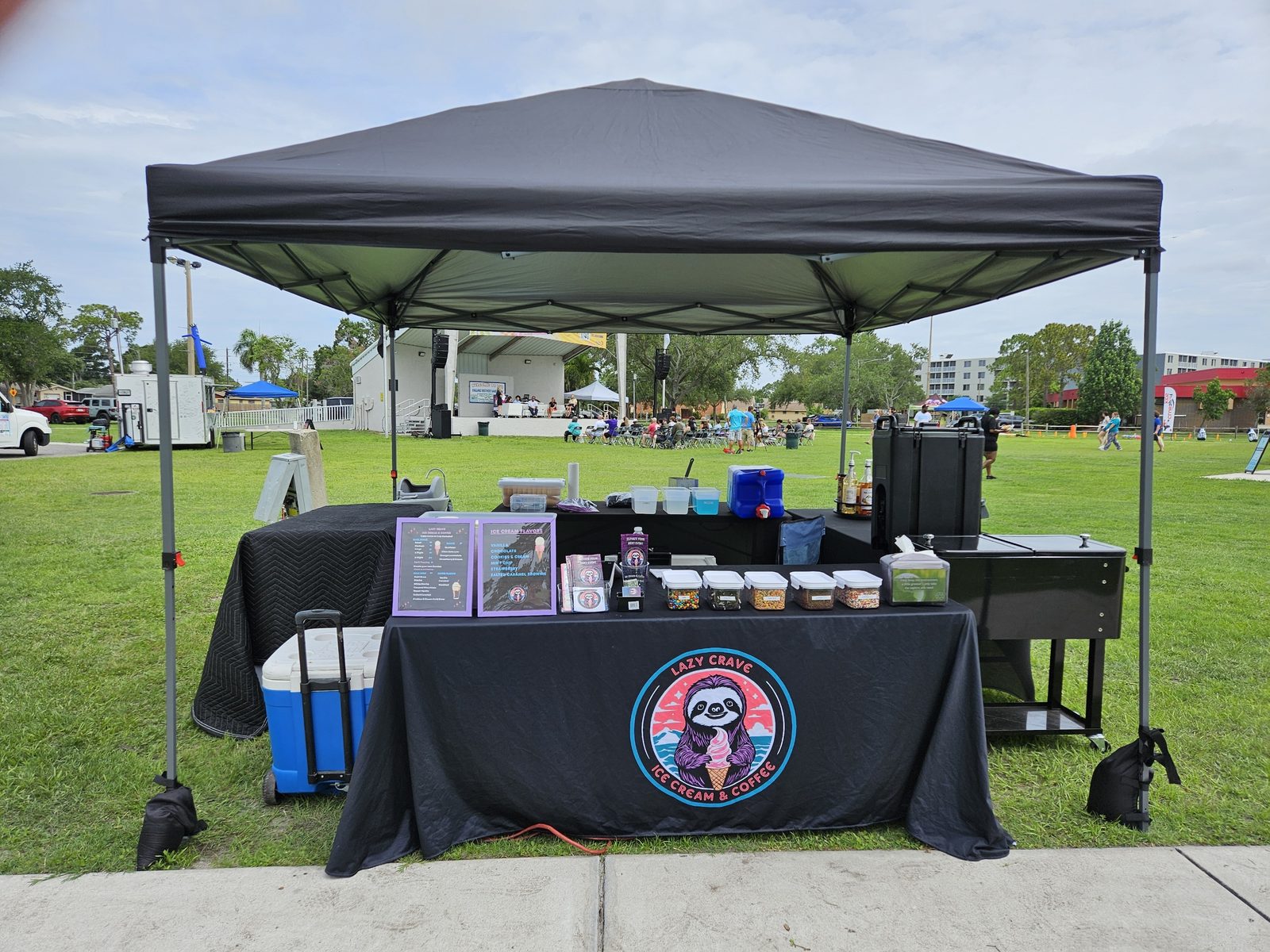 Lazy Crave's tent and table setup with toppings bar at a park event