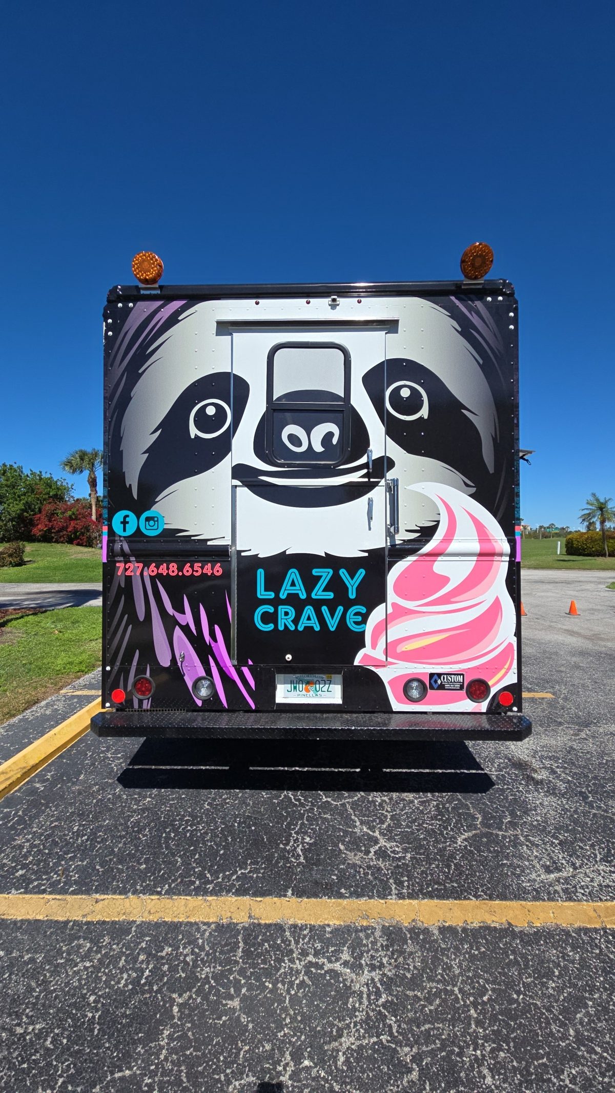 The back of the Lazy Crave truck, painted with a giant smiling sloth face