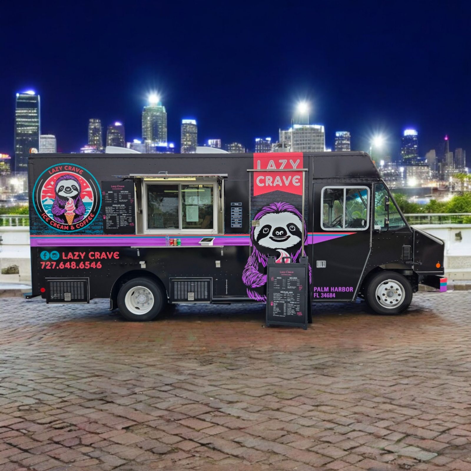 The Lazy Crave truck parked with its window open and menu board out, city skyline glowing behind it